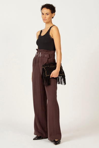 T-shirt noir Astrid Black Label avec des détails sur les bords le la ligne du cou, porté avec un pantalon brun à taille haute et une pochette noire.