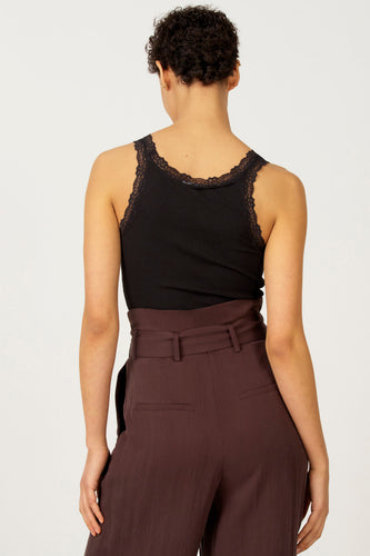 Zwarte singlet van Astrid Black Label met kanten details langs de halslijn en schouders, gedragen met een bruine pantalon.
