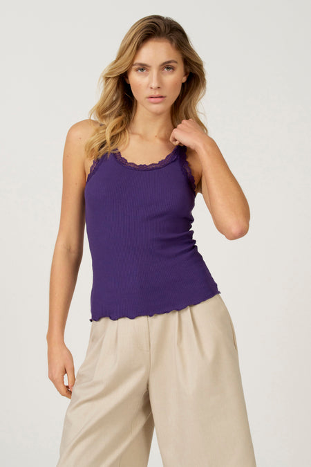 Paarse singlet van Astrid Black Label met kanten details, gecombineerd met een losse, beige broek.
