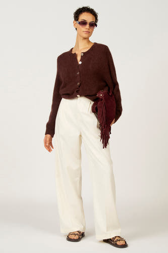 Gilet marron d'Astrid Black Label, porté sur un cardigan marron et des pantalons beige, avec une poche frangée.