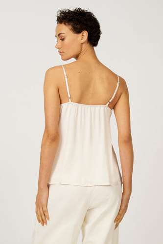 Ecru mouwloze blouse van Astrid Black Label, met dunne schouderbandjes en gedragen met bijpassende ecru broek.
