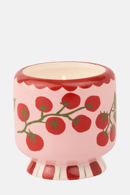 Rode kaars van PADDY WAX met tomatenprint en een rood randje aan de bovenkant, op een gestreepte voet.
