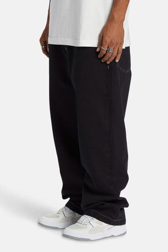 Zwarte wijde jeans van DC SHOES, met een losse pasvorm en witte sneakers.