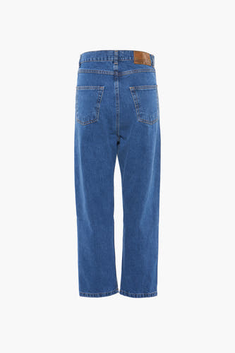 Jean large en denim bleu moyen de KAOTIKO, avec des poches arrière et une étiquette de marque en cuir brun.