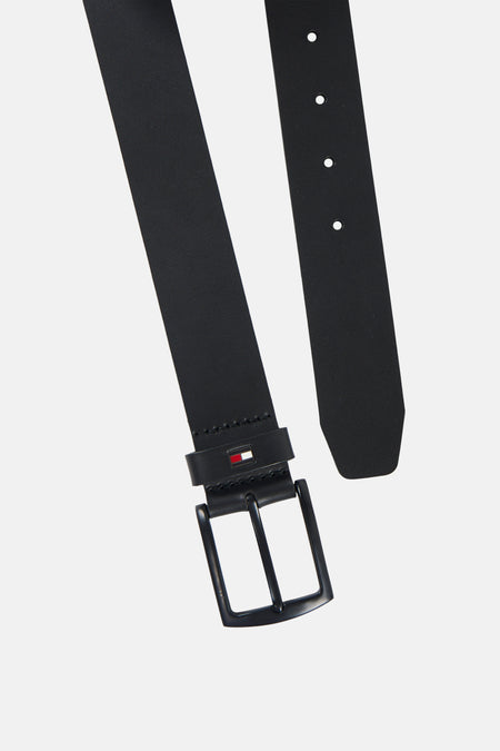 Ceinture noire TOMMY JEANS, présentée en diagonale, avec une boucle métallique, des perforations et le logo drapeau sur le passant.