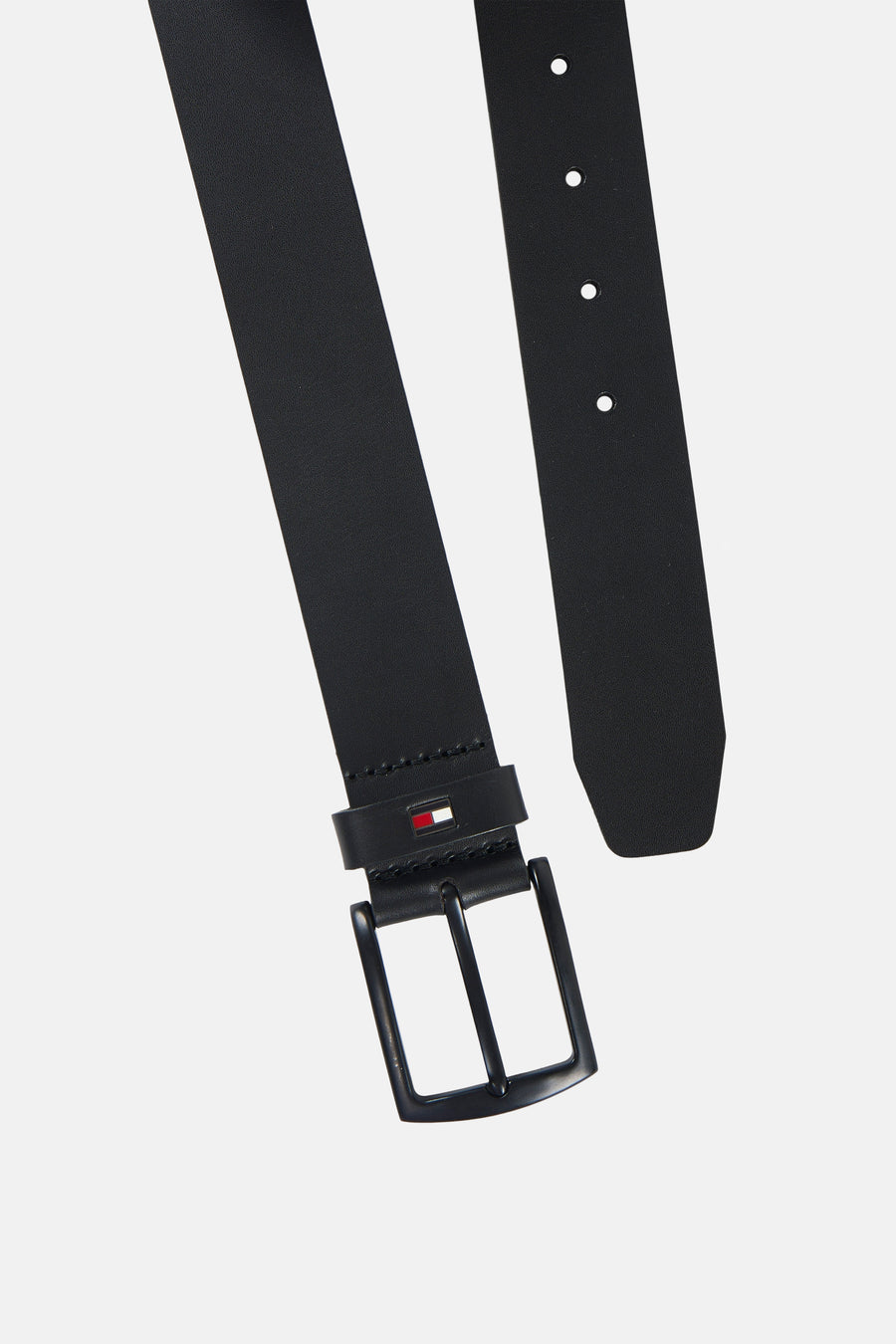Zwarte riem van TOMMY JEANS, diagonaal getoond, met een metalen gesp, perforaties en vlaglogo op de passant.