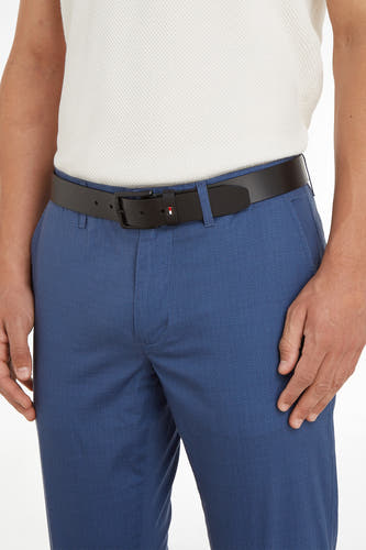 Zwarte riem van TOMMY JEANS, met een subtiel logo op de gesp, gedragen met een blauwe broek en een witte top.
