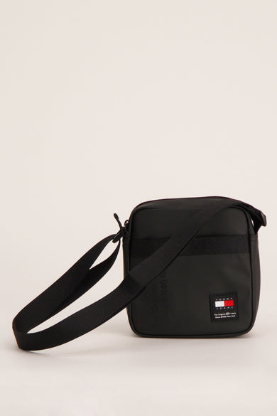 Zwarte schoudertas van Tommy Jeans, met verstelbare schouderband en logo-patch op de voorzijde.