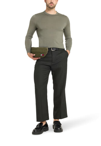 Sac à dos vert de TOMMY JEANS, porté avec un pull gris, un pantalon noir et des loafers noirs.