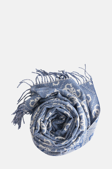 Blauwe wintersjaal van Guess met wit patroon en franjes, opgerold gepresenteerd.
