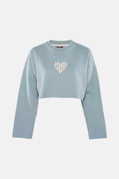 Turquoise sweater van KAOTIKO, met een geborduurd logo in de vorm van een hart op de borst, cropped model.
