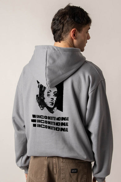 Gilet gris avec capuche de KAOTIKO, imprimé noir d'un visage et texte répété sur le dos.