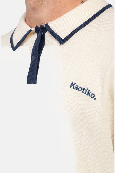 Ecru trui met ronde hals van KAOTIKO, ribgebreid met een marineblauwe kraag en logo.
