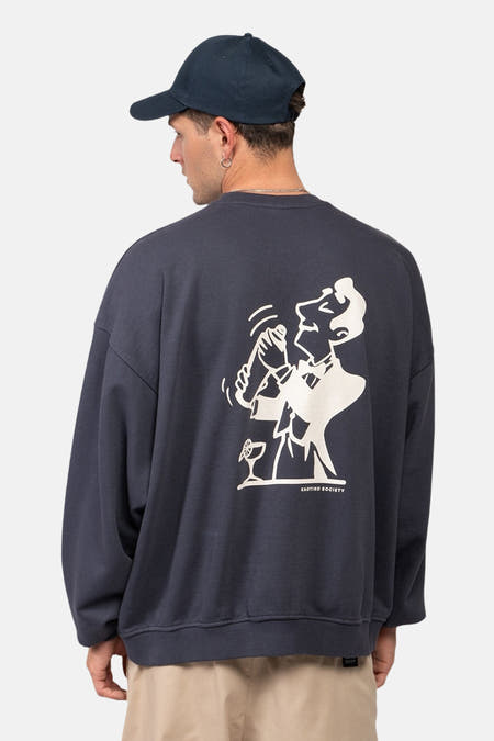 Blauwe sweater van KAOTIKO, met een witte illustratie van een barman op de rug.