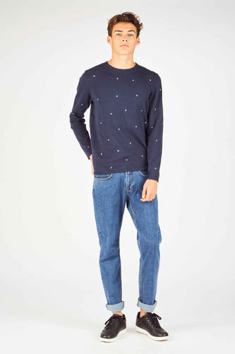 Rechte jeans in middenblauw denim van MAC, met omgeslagen pijpen en gecombineerd met een donkerblauw shirt en zwarte sneakers.