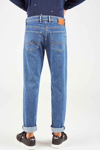 Mid blue straight jeans van MAC met opgerolde pijpen en zichtbare zwarte schoenen.