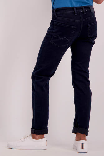 Donkerblauwe straight jeans van MAC, met zichtbare achterzakken en witte sneakers.