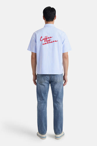 Blauw gestreept overhemd met korte mouwen van KAOTIKO, met rode opdruk op de rug, gecombineerd met jeans en sneakers.