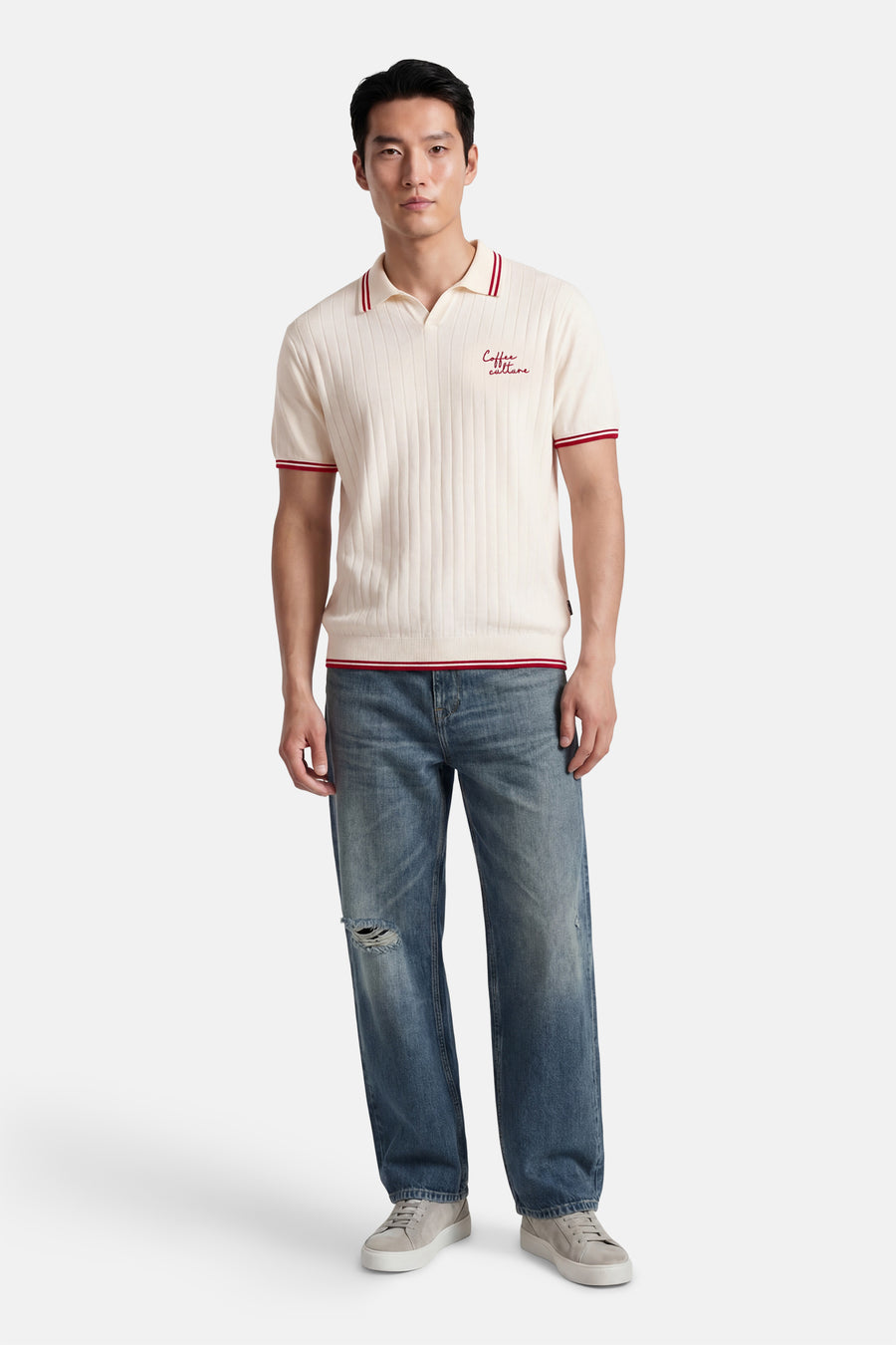 Witte polo van KAOTIKO met korte mouwen, rode accenten en een geborduurde tekst.