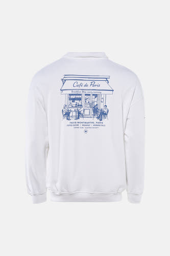 Witte sweater van KAOTIKO met een blauwe print van een Parijs café op de achterkant.
