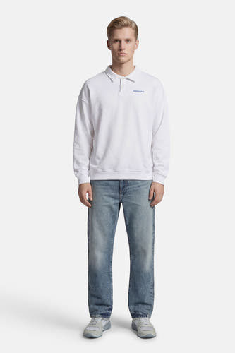 Witte sweater van KAOTIKO, met lange mouwen, gedragen met blauwe jeans en grijze sneakers.