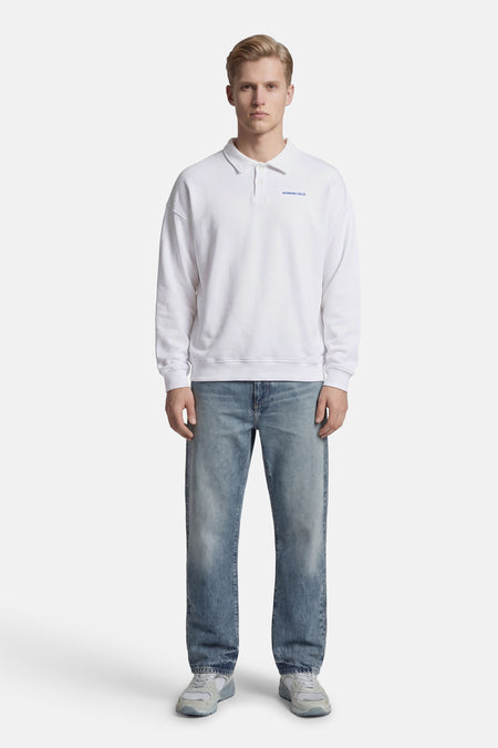Witte sweater van KAOTIKO, met lange mouwen, gedragen met blauwe jeans en grijze sneakers.
