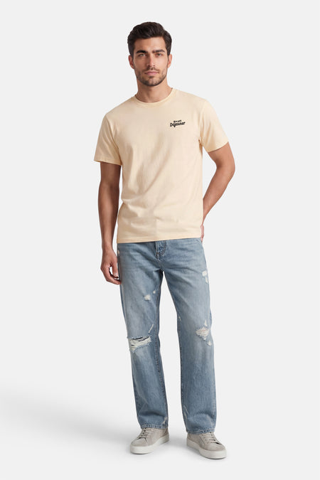Ecru T-shirt van KAOTIKO, met korte mouwen en een kleine tekstprint, gecombineerd met een ripped jeans en sneakers.
