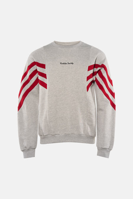 Grijze sweater van KAOTIKO, met rode strepen op de mouwen en een ronde hals.
