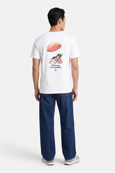 Wit T-shirt van KAOTIKO met achterop een print van een ontspannen hond onder een parasol, van achteren gezien.