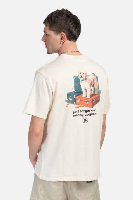 T-shirt écru de KAOTIKO avec un imprimé de chien sur une pile de valises au dos.