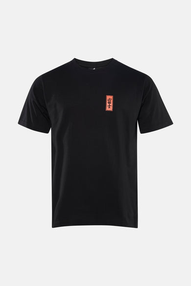 T-shirt noir à manches courtes de KAOTIKO avec un badge rectangulaire orange sur la poitrine.