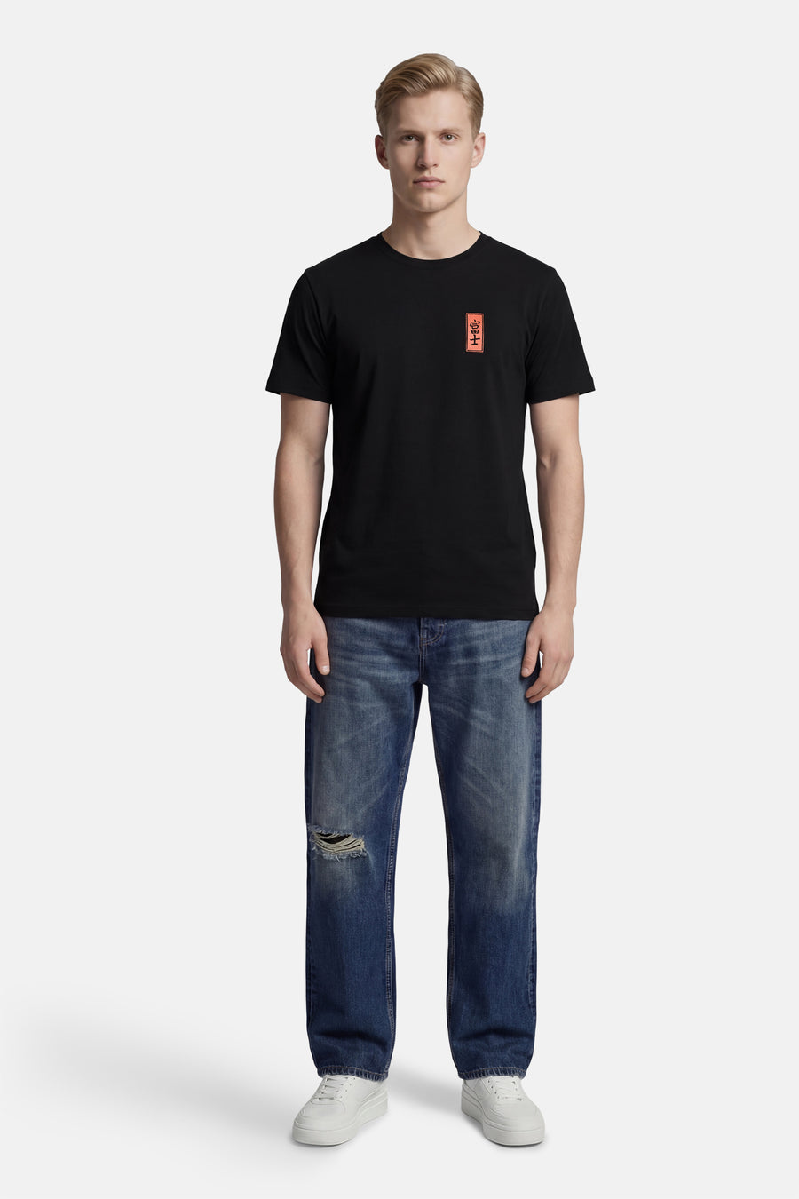 T-shirt noir à manches courtes de KAOTIKO, avec un petit écusson rouge, combiné avec un jean bleu et des baskets blanches.