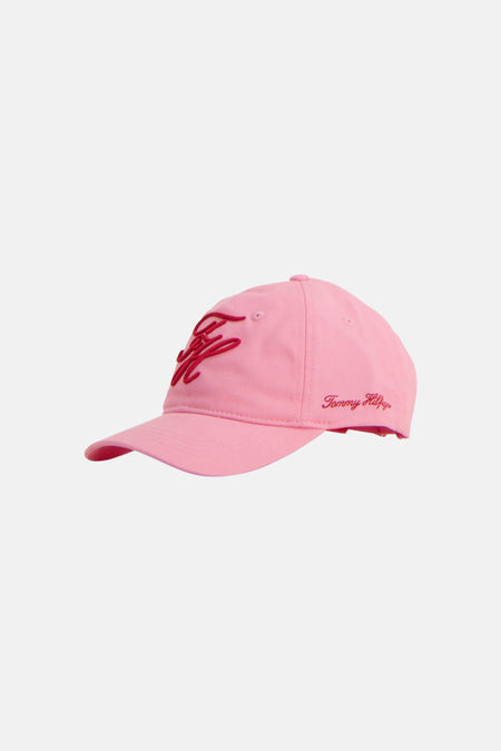 Casquette rose de TOMMY JEANS, avec grand logo script brodé rouge sur le devant et signature 'Tommy Hilfiger' sur le côté.