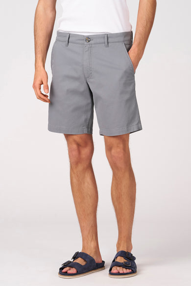 Blauwe bermuda van Bruce & Butler, gedragen met een wit shirt en blauwe sandalen.
