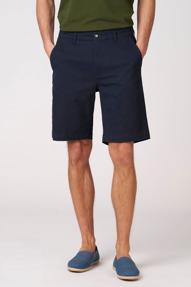 Blauwe bermuda van Bruce & Butler, met steekzakken en gedragen met blauwe espadrilles.
