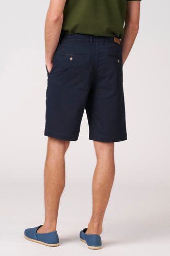 Blauwe bermuda van Bruce & Butler, gezien van achteren, met zakken en blauwe espadrilles.
