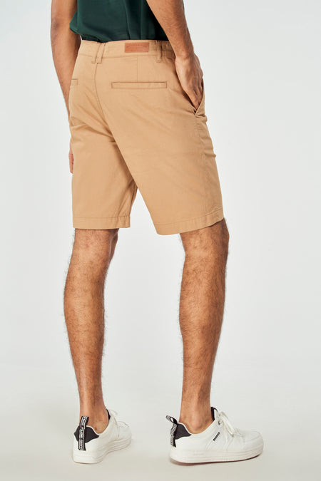 Bruine short van Bruce & Butler, achterkant gezien, met steekzak en witte sneakers.
