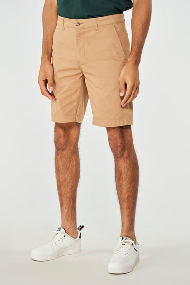 Bruine short van Bruce & Butler, met een effen dessin, gedragen met een groen shirt en witte sneakers.
