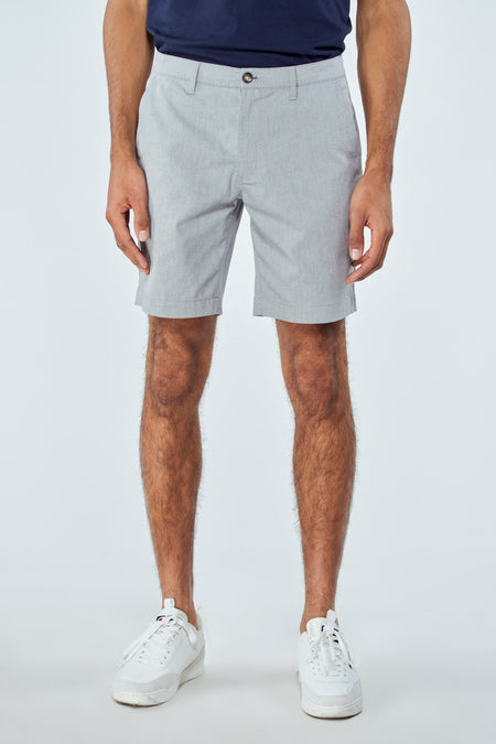 Blauwe short van Bruce & Butler, gedragen met witte sneakers en een donkerblauw shirt.
