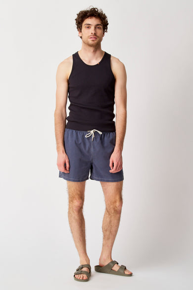 Jean bleu de Bruce & Butler, porté avec un tank-top noir et des sandales vertes.