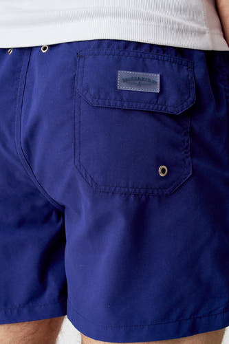 Blauwe zwembroek van Bruce & Butler, met achterzak en zilverkleurige details, cropped.
