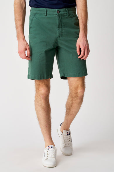 Groene short van Bruce & Butler, met een zichtbare knoop en gedragen met witte Champion schoenen.
