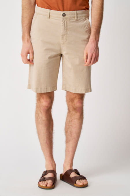 Beige short van Bruce & Butler, gedragen met bruine sandalen en oranje shirt, cropped.
