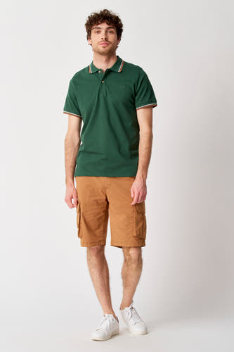 Bruine short van Bruce & Butler, met zakken op de zijkant, gecombineerd met een groene polo en witte sneakers.