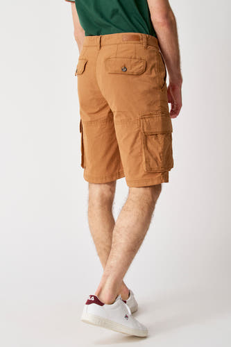Bruine korte broek van Bruce & Butler, met cargozakken en gedragen met een groen shirt en witte sneakers.
