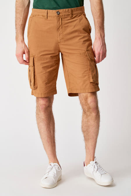 Bruine short van Bruce & Butler, met cargo zakken en gecombineerd met witte sneakers.
