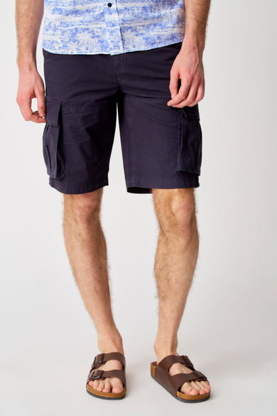 Short bleu de Bruce & Butler, porté avec des sandales brunes et un chemisier bleu clair.