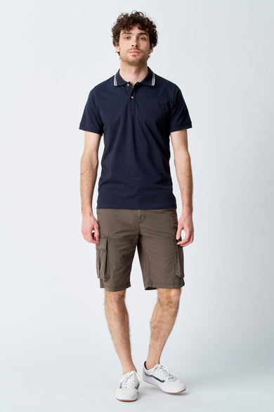 Kaki korte broek van Bruce & Butler, met cargozakken, gecombineerd met een marineblauw poloshirt en witte sneakers.
