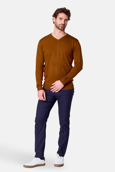 Pull brun avec col V de Bruce & Butler, porté avec un pantalon bleu marine et des baskets blanches.