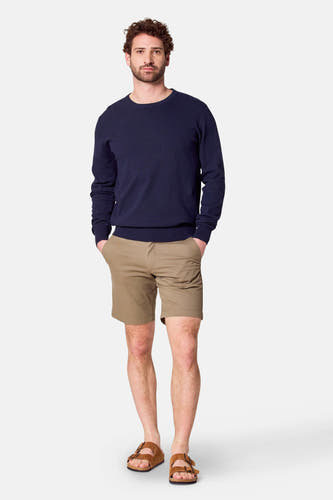 Donkerblauwe trui met ronde hals van Bruce & Butler, gedragen met kaki shorts en bruine sandalen.
